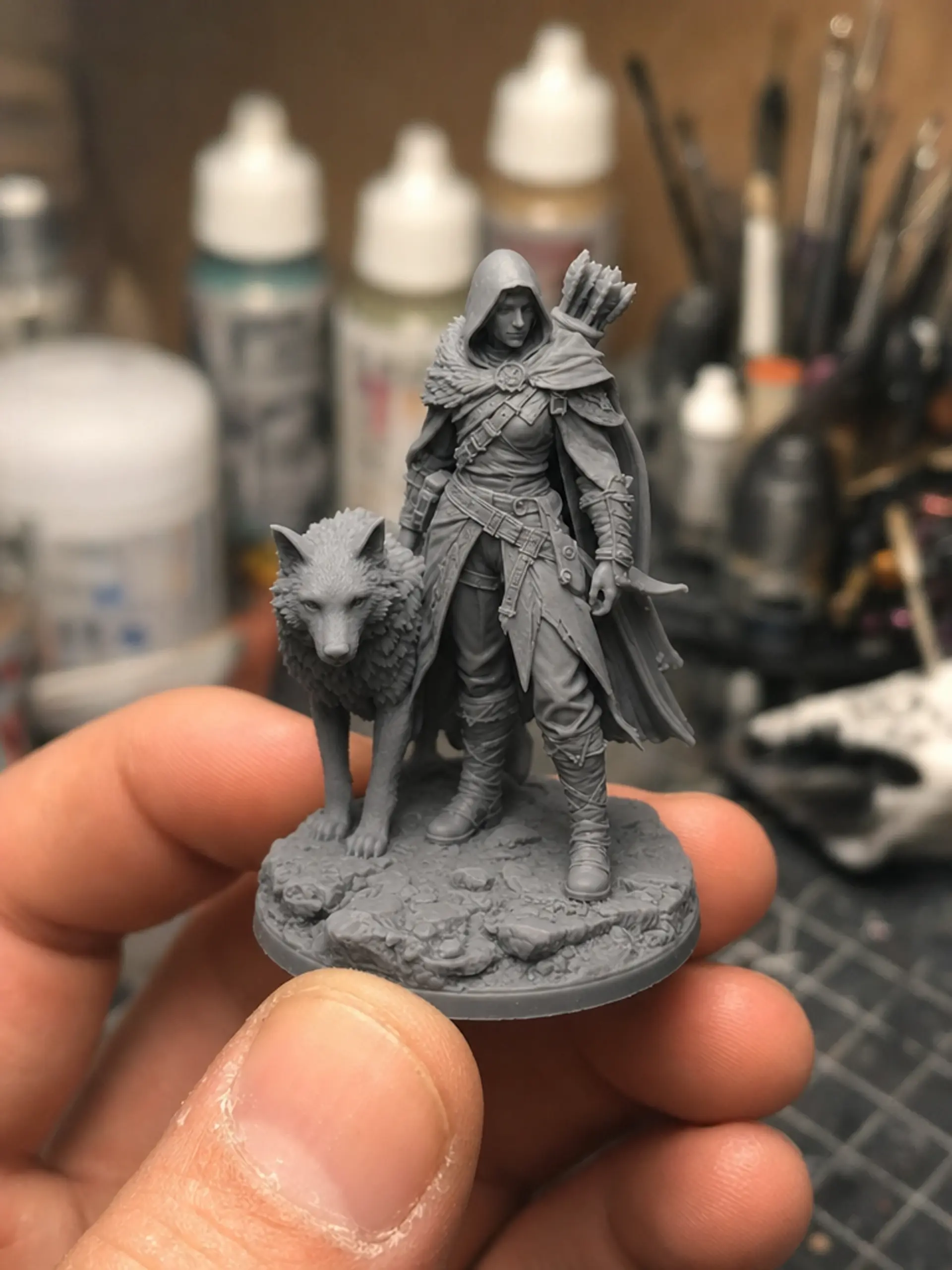 The printed grey resin ranger and wolf miniature held in a hand